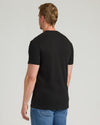 Man wearing a black t-shirt and blue jeans on a light gray background