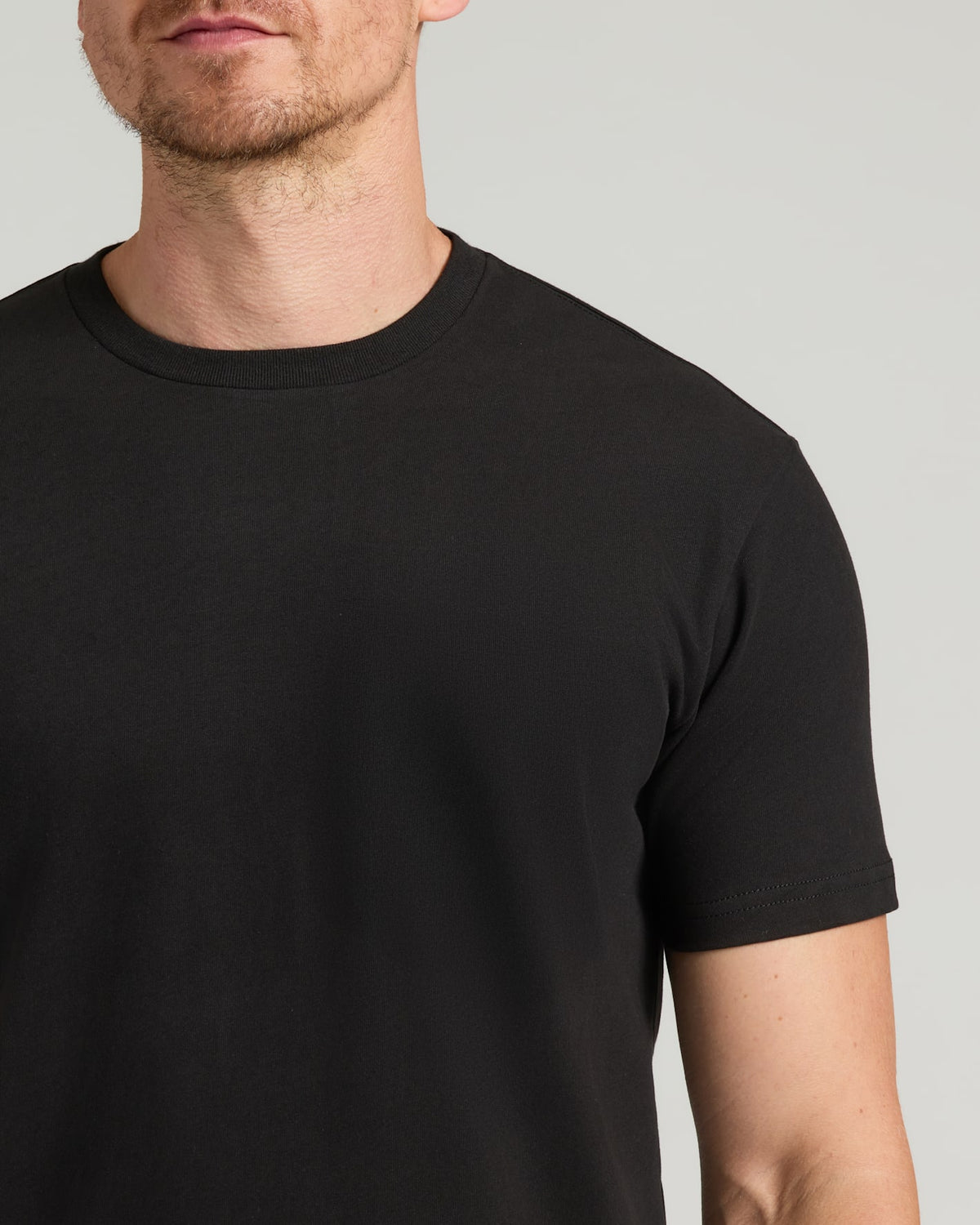 Person wearing a plain black t-shirt against a neutral background
