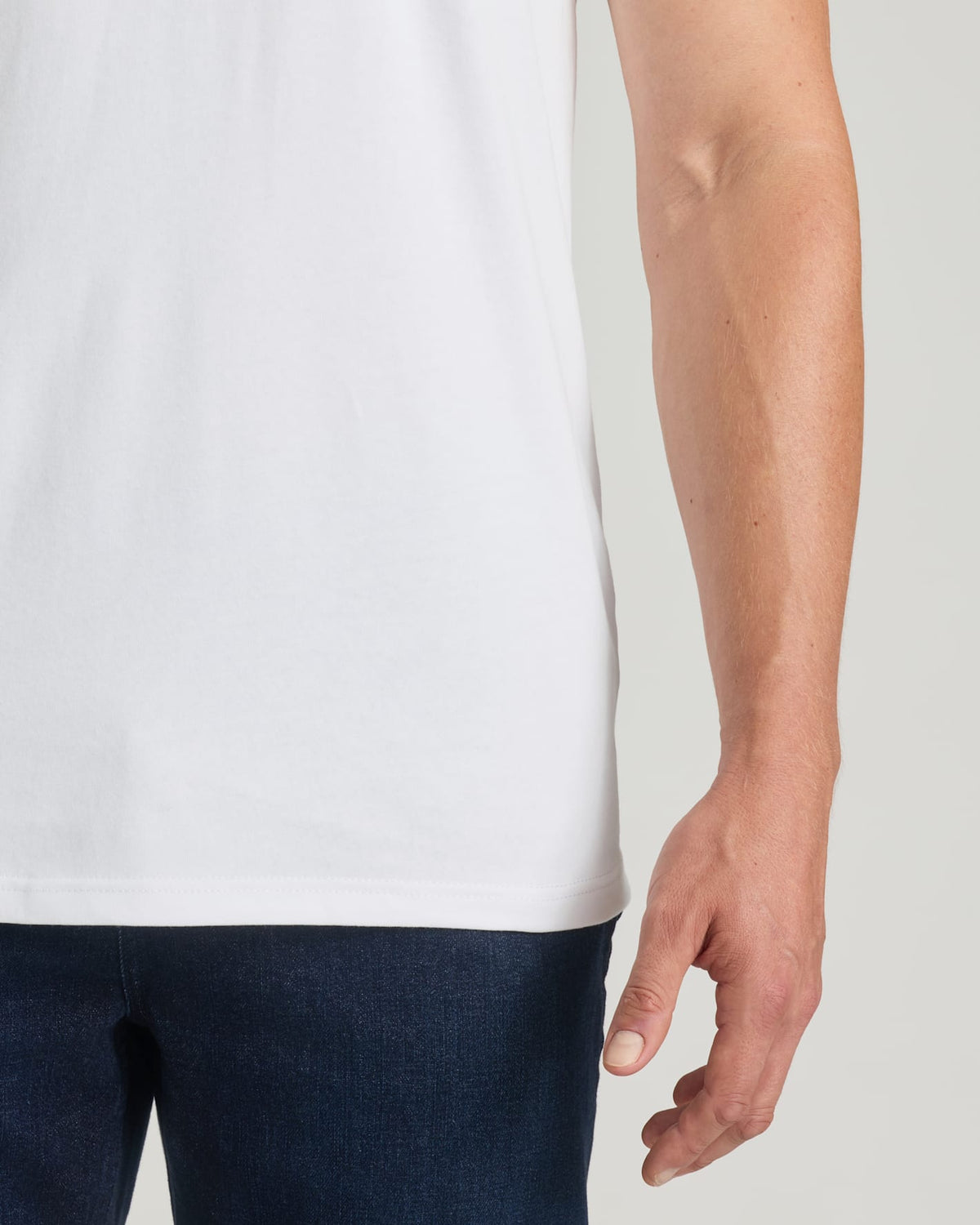 Person wearing a plain white t-shirt and dark pants on a light background