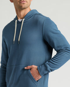 True ClassicMan wearing a blue Fiord Fleece French Terry Pullover Hoodie with white drawstrings and a front pocket, showcasing comfortable men's basics in casual wear.