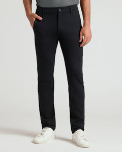 True ClassicA person wearing slim-fit black trousers, paired with a gray top and white sneakers, standing against a light gray studio background.