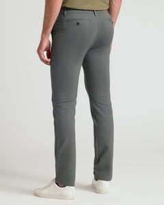 True ClassicA person shown from the back wearing slim-fit gray trousers, a muted olive green top, and white sneakers against a clean light gray studio background.