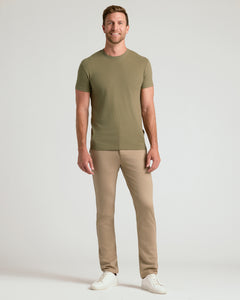True ClassicA man modeling a short-sleeve crewneck t-shirt in olive green and beige trousers, standing against a light gray studio background.