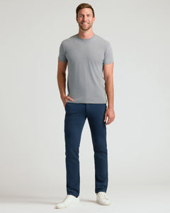 True ClassicA man modeling a light gray crew-neck t-shirt and navy blue pants against a plain light gray studio background.