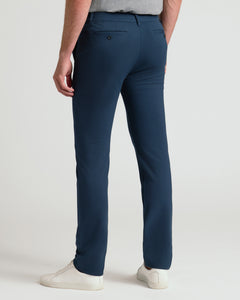 True ClassicA person shown from the back wearing navy blue slim-fit trousers, a gray top, and white sneakers against a clean light gray studio background.