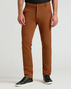True ClassicA person wearing slim-fit brown trousers with a black shirt and black sneakers, standing against a light gray studio background.