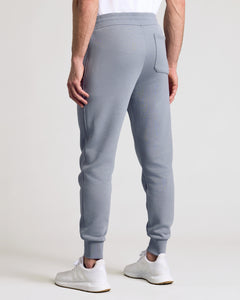 True ClassicDusty Blue Fleece French Terry Joggers with white sneakers, rear view.