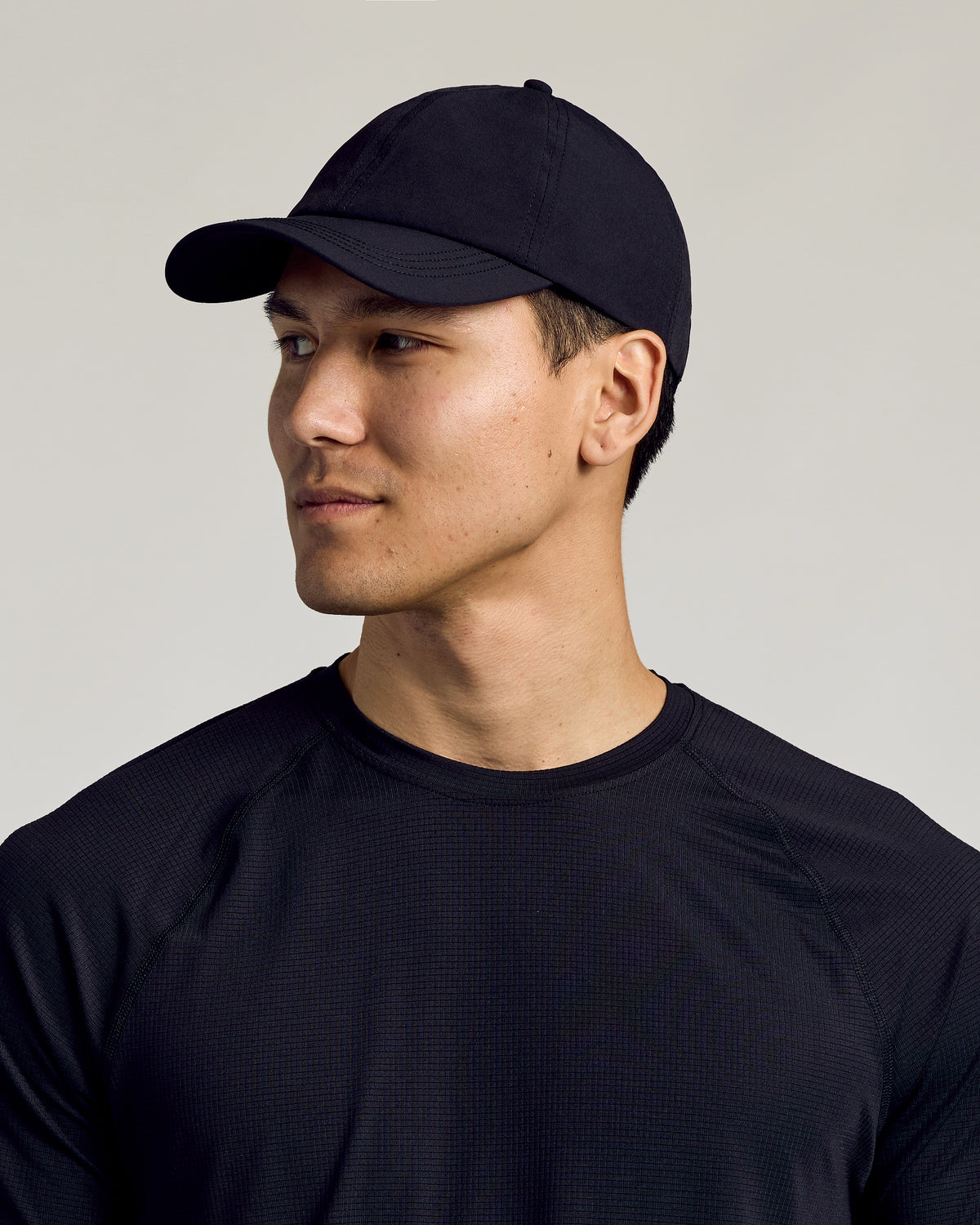 Black Active Running Cap on young man, slightly turned, looking off-camera.