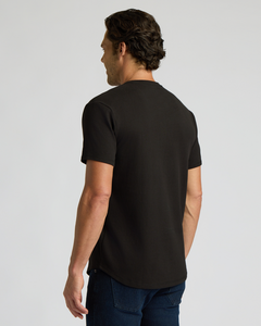 True ClassicMan wearing an all black short-sleeve shirt with a curved hem, shown from the back, featuring the All Black Heavyweight Curved Hem Henley 3-Pack as a men's basics essential.