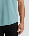 Close-up of a person wearing a light blue Citadel Heavyweight Curved Hem Henley paired with black pants, showcasing the curved hem detail and casual men's basics style.
