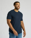 Smiling man wearing a navy blue Tall Heavyweight Curved Hem Crew 3-Pack t-shirt paired with jeans, showcasing a comfortable and stylish men's basic from True Classic.