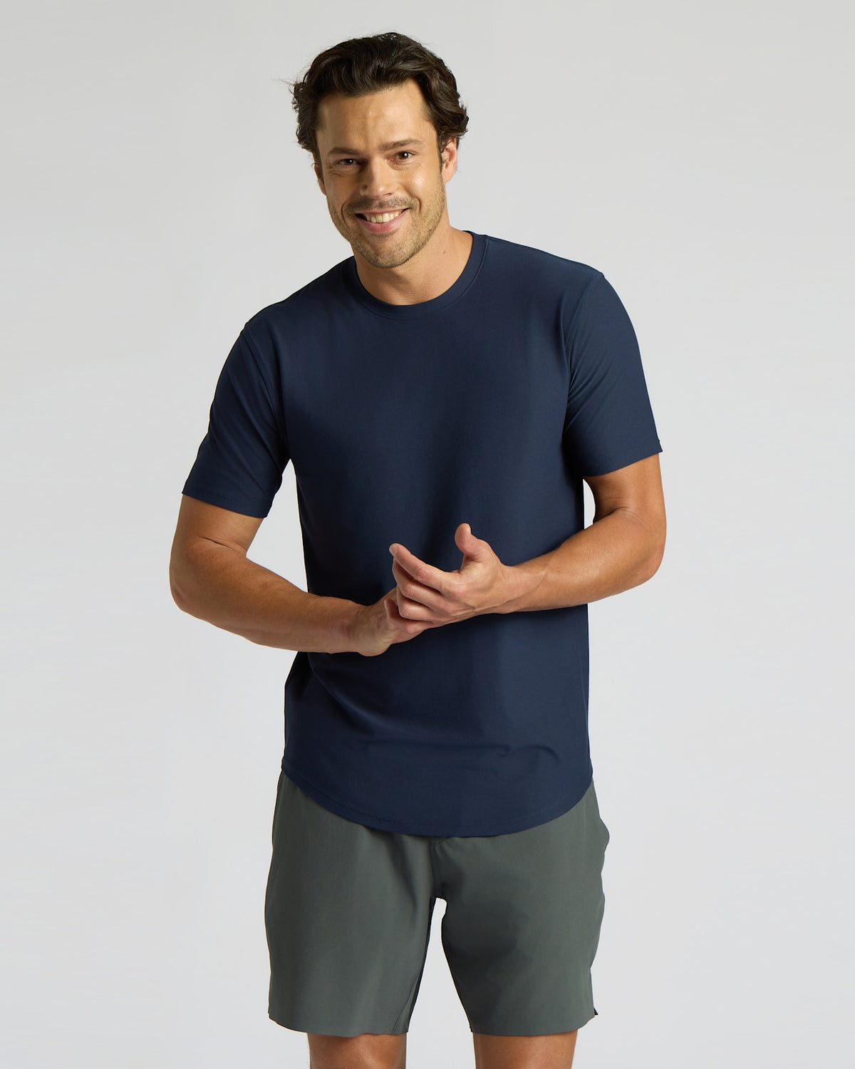 Man wearing a navy blue t-shirt and gray shorts on a light gray background