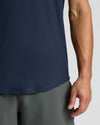 Person wearing a navy sleeveless shirt and gray pants on a light gray background