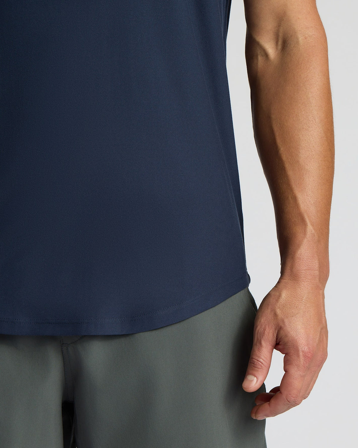 Person wearing a navy sleeveless shirt and gray pants on a light gray background