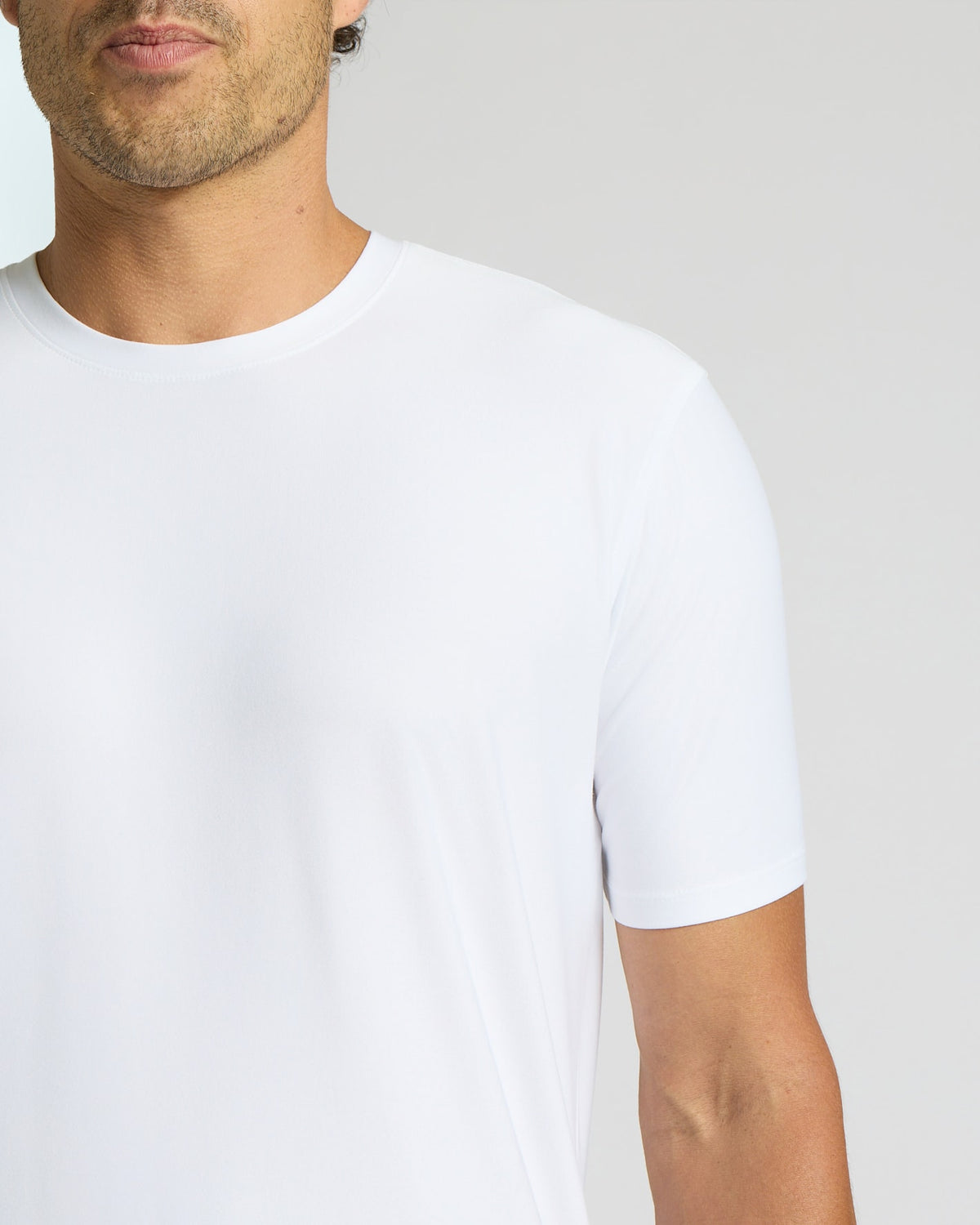 Man wearing a plain white t-shirt against a light gray background