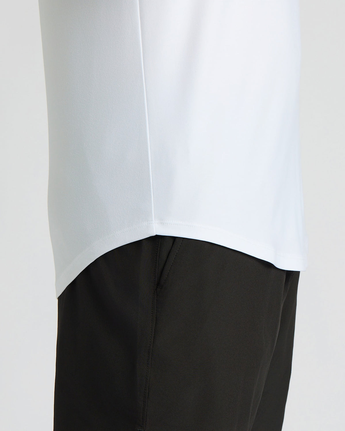 Close-up of a man wearing the All White Active Curved Hem Crew 6-Pack shirt, showing the curved hem detail over black athletic pants as a men's basics essential.