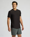 Man wearing a black t-shirt and gray shorts on a light gray background