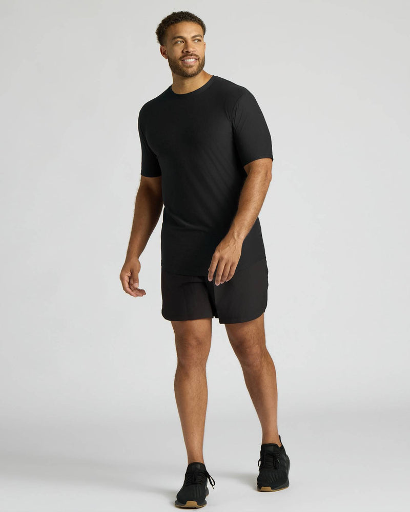 Man wearing a black t-shirt and shorts on a light gray background