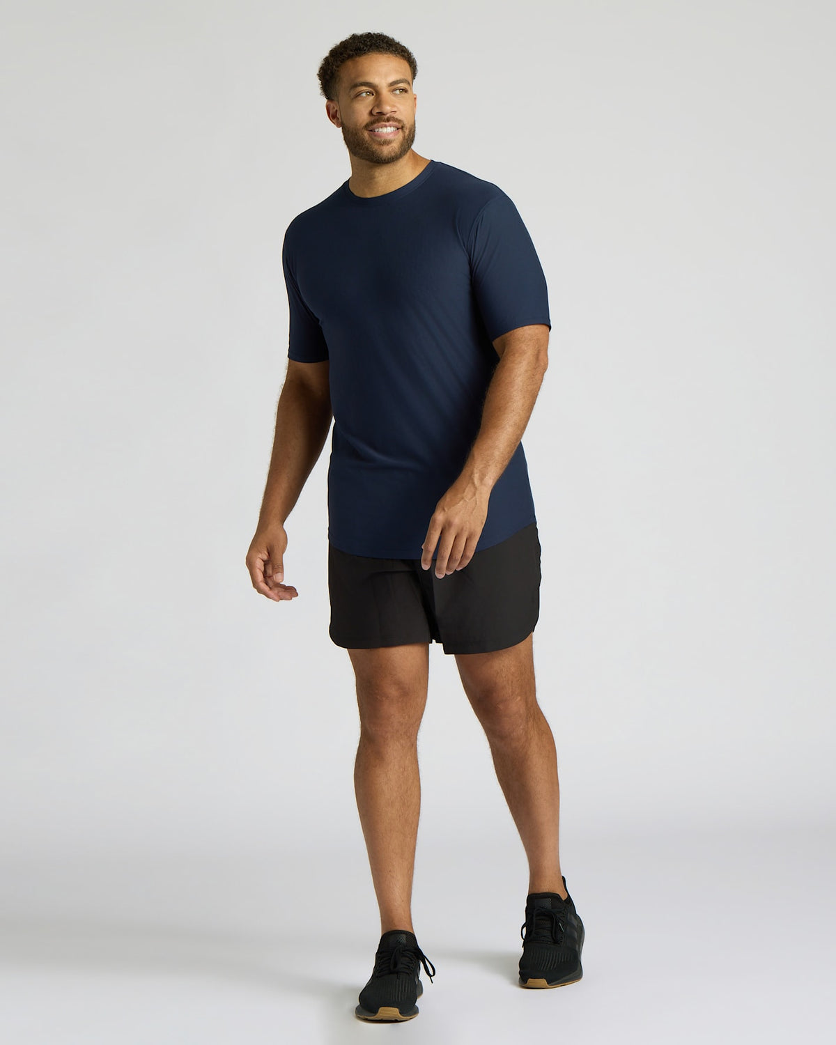 Man wearing a navy blue Tall Active Curved Hem Crew 6-Pack shirt paired with black shorts and sneakers, showcasing a comfortable and stylish men's basics activewear look.