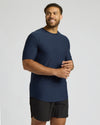 Man wearing a navy blue t-shirt and black shorts on a light gray background