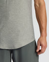 Close-up of a person wearing a heather gray athletic tank top and dark gray athletic shorts against a light gray studio background.