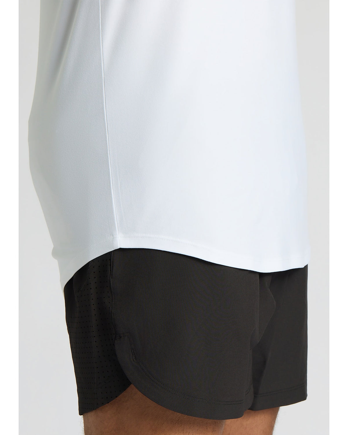 Person wearing a white long-sleeve shirt and black shorts on a light gray background