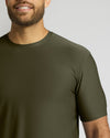 A close-up of a man wearing a short-sleeve crew-neck t-shirt in olive green, showing the fabric texture and fit against a light gray background.