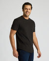 Man wearing a black Heavyweight Curved Hem Crew 3-Pack t-shirt with a relaxed fit and crew neckline, styled with dark denim jeans in a studio setting.