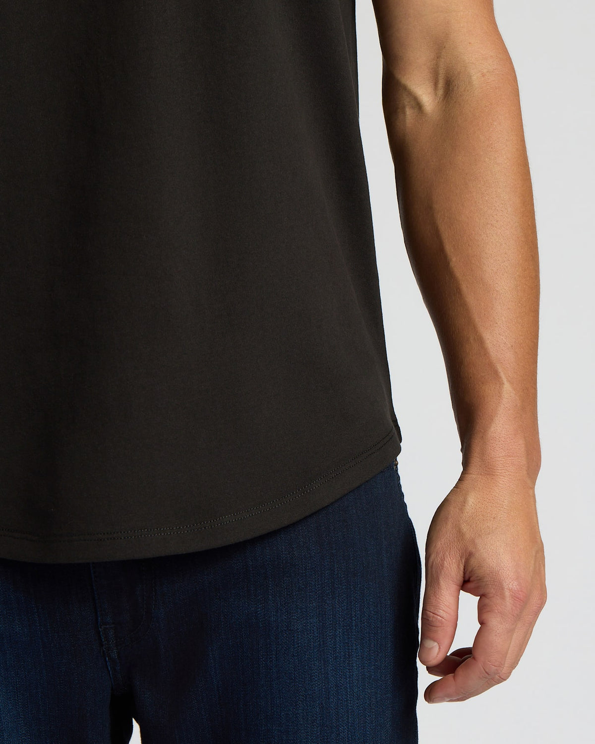 Close-up of a man wearing an All Black Heavyweight Curved Hem Crew 6-Pack shirt paired with dark blue jeans, highlighting the curved hem detail on the black heavyweight fabric.