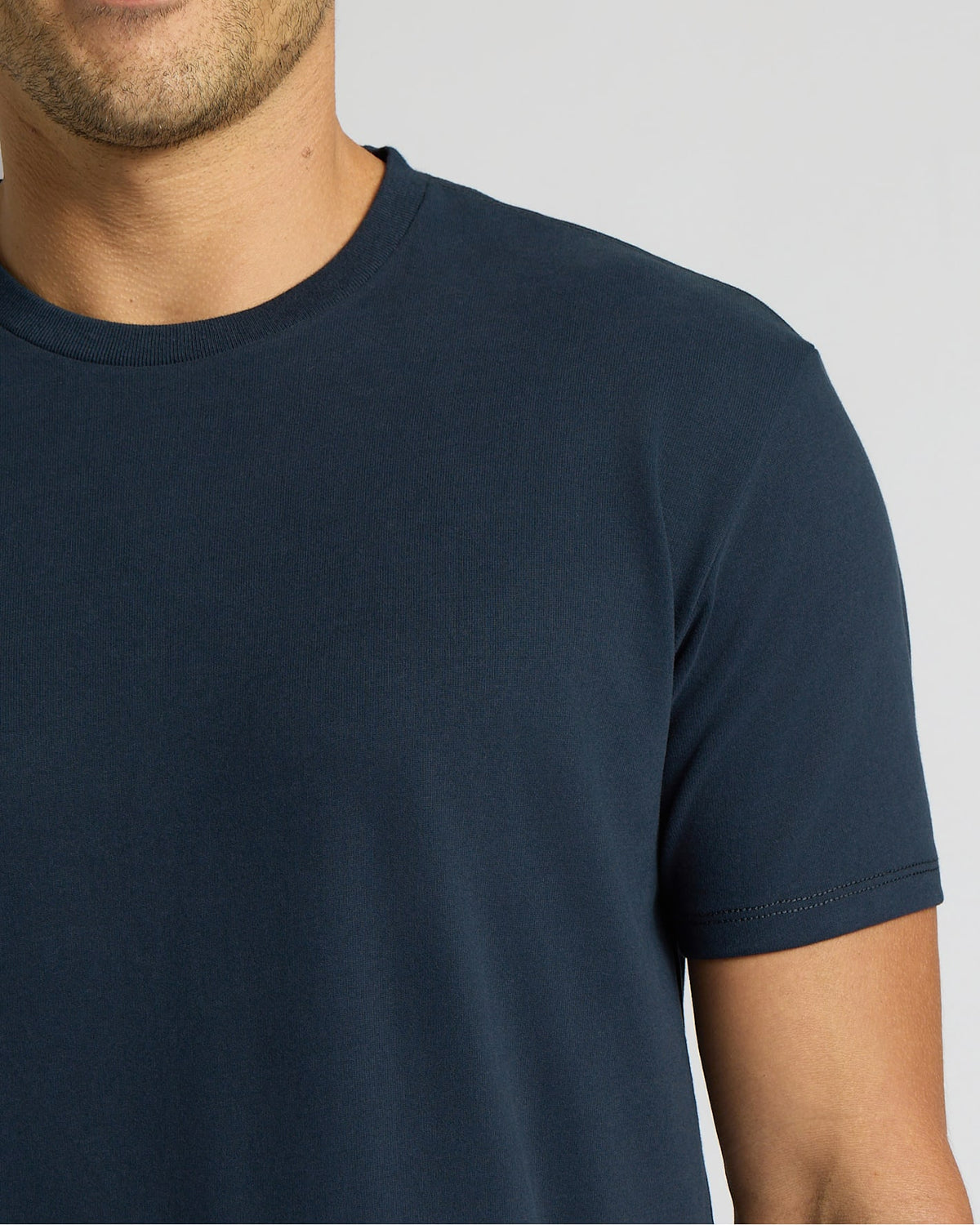 Close-up of a man wearing a Navy Heavyweight Curved Hem Crew, a classic men's basics t-shirt in solid navy blue with a crew neckline and short sleeves.