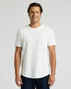 Man wearing a white Heavyweight Curved Hem Crew 6-Pack t-shirt, standing and smiling with a clean, minimal background, showcasing a classic men's basics style.