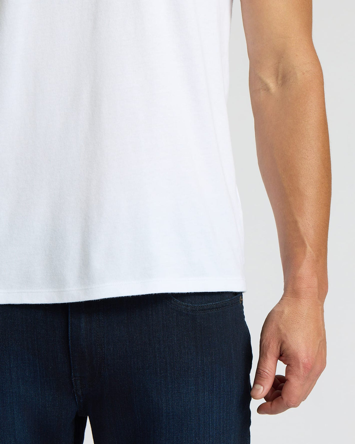 Person wearing a white t-shirt and dark pants on a plain background