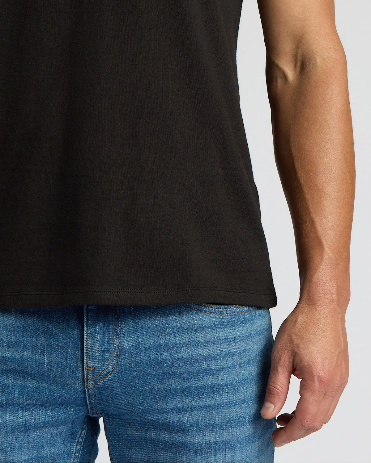 Person wearing a black t-shirt and blue jeans on a plain background