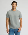 Man wearing a gray t-shirt and blue jeans on a light gray background