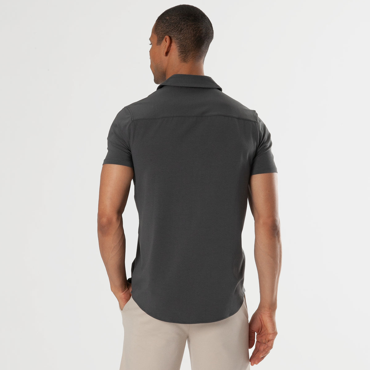 Man wearing Carbon Short Sleeve Knit Shirt with khaki pants, back view.