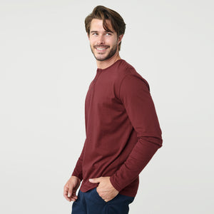 True ClassicMan wearing Burgundy Classic Long Sleeve Henley, smiling slightly, hand in pocket.